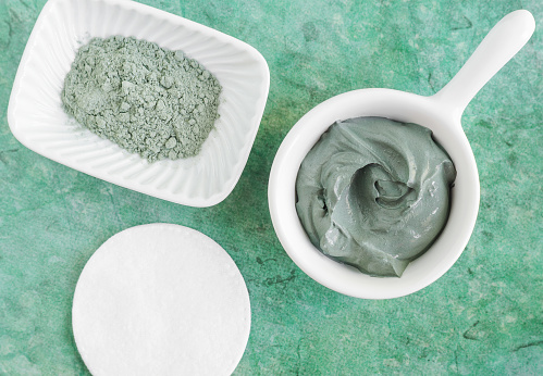 Green (blue, grey) bentonite clay in a bowl. Clay texture close up. Diy mask and body wrap recipe. Natural beauty treatment and spa. Top view, copy space