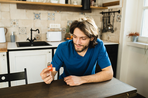Smiling young man removing beer bottle from refrigerator at home