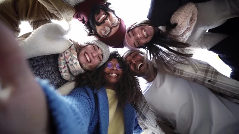 Internacional Erasmus students looking at camera cheerfully embracing each other.