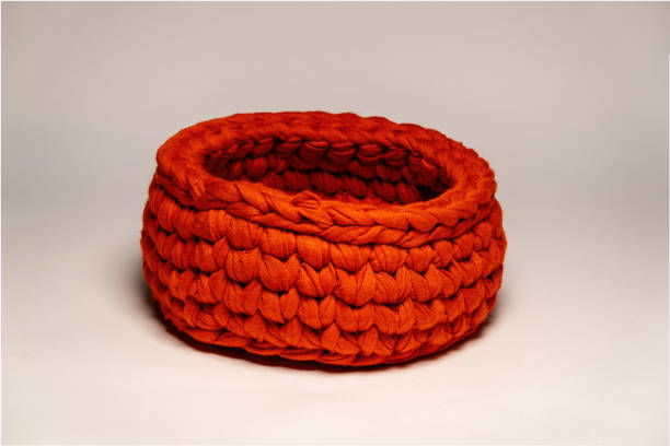 istock Recycling of materials. A small knitted container in red color is made from fabric strips. For storing small things 1456170198