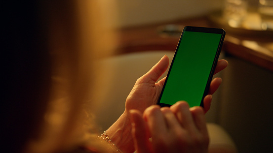 Closeup hand touching green screen device. Woman scrolling chroma key gadget. Unrecognized aircraft passenger businesswoman holding template cellphone checking email feed. Business leisure concept.