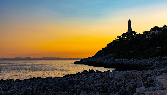 Saint Jean Cap Ferrat, France - August 3, 2022: Sunset evening landscape of southern rocky shore of Cap Ferrat cape at French Riviera of Mediterranean Sea with Le Phare Lighthouse