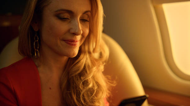 istock Smiling woman flying jet closeup. Happy passenger using smartphone on plane. 1456171820