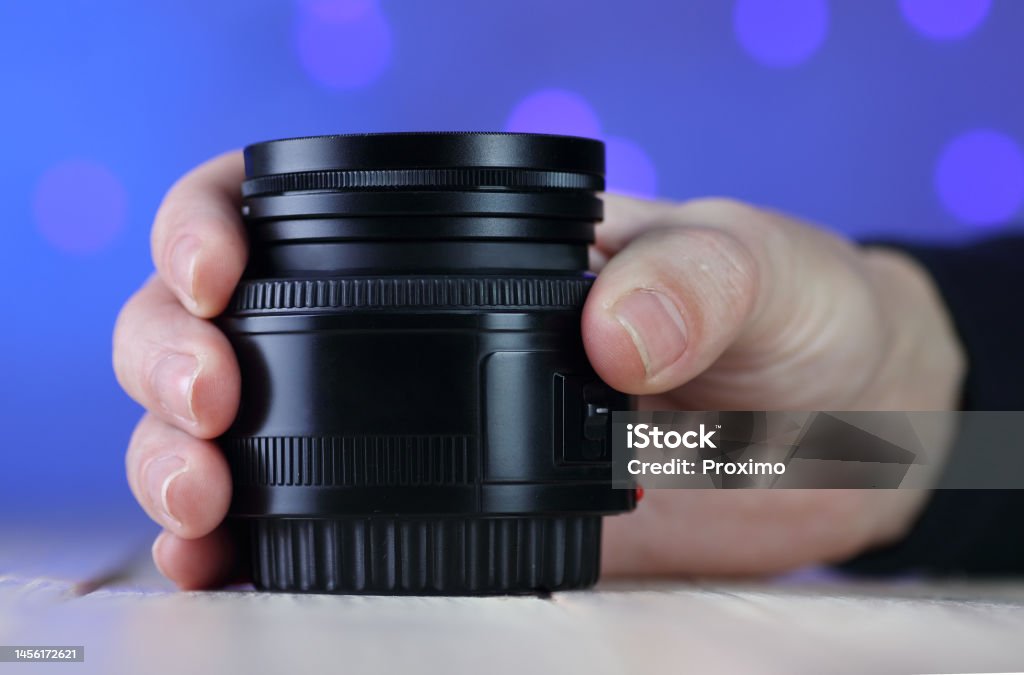 50mm lens in hand on table 50mm lens in hand on table and colored background Blue Background Stock Photo