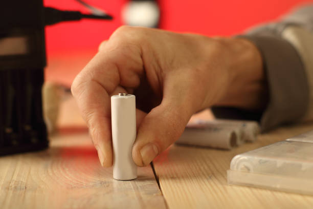 istock one battery held in fingers on table 1456172754