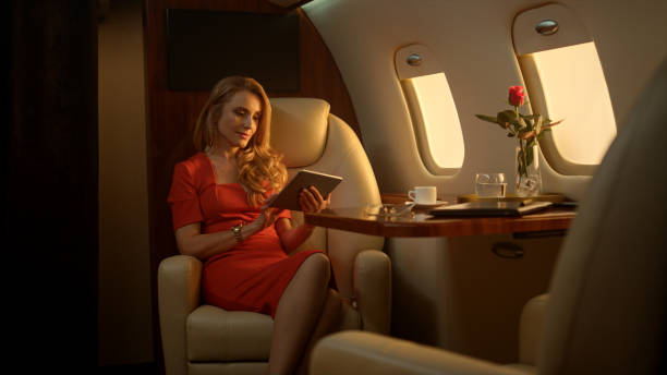 istock Smiling businesswoman enjoying tablet computer on luxury private jet sunlight. 1456174860