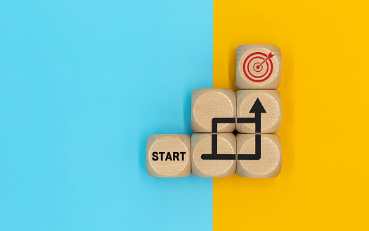 Starting point and a wooden cube with an arrow pointing to the target icon. Growing business success concept
