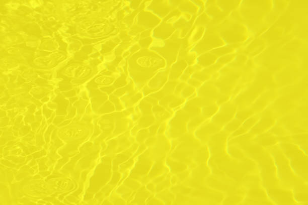 istock Defocus blurred transparent yellow colored clear calm water surface texture with splashes and bubbles. Trendy abstract nature background. Water waves in sunlight with caustics. Gold watercolor shine 1456176470