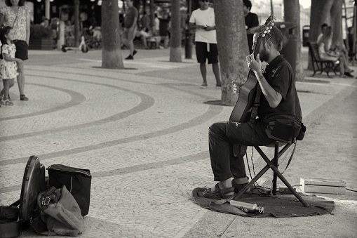 Lisbon, Portugal - August 13, 2022: A street musicians performs at a public garden in Lisbon downtown.