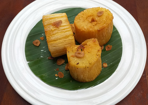 Traditional Indonesian Food - Fried Cassava or Singkong Goreng served on a banana leaf on a white plate. This dish is also called Brazilian Mandioca Frita.