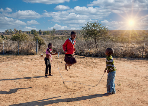 african kids, group of friends skipping rope in the yard, village in botswana