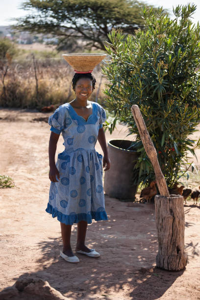 young african woman with braids grinding cereals in a manual pest and mortar