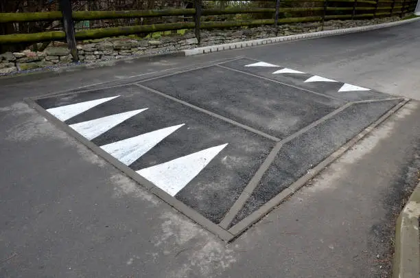 in the middle of the road leading to the residential area, the police and the traffic office installed a red plastic retarder. raised square made of rubber beveled on the sides, arrow, triagle, roadway, speed-bump