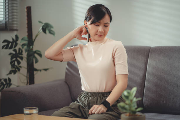 自宅の居間のソファに座って耳に指を入れるアジアの女性。 - cotton swab audio ストックフォトと画像
