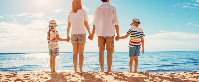 Mother and father with their children standing on the beach on the resort. Concept of the family vacation and tourism.