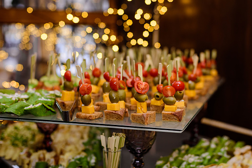 Canapes on wooden skewers on a buffet or banquet. Catering.