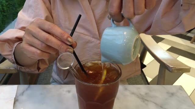 Unrecognizable Woman Pouring Liquid Sugar Into Her Ice Lemon Tea