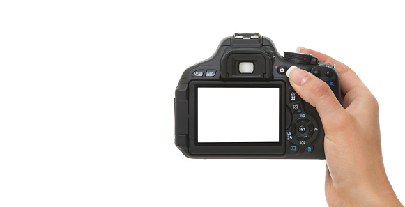 Digital DSLR camera in a young woman's hand against a white background with copy space