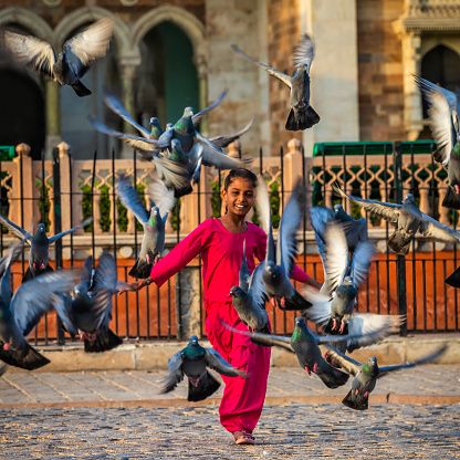 Little girl playing with pigeons, Jaipur, India. Jaipur is known as the Pink City, due to the dominant colour of its buildings.