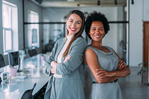 Shot of two confident businesswomen standing side by side and keeping arms crossed while looking at camera.