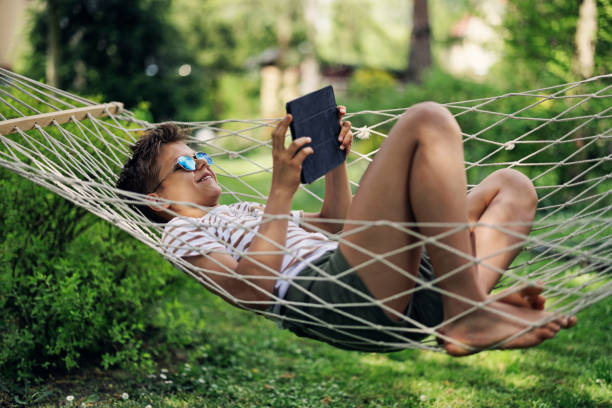 istock Teenage boy playing with tablet on a hammock on a spring day 1456195198