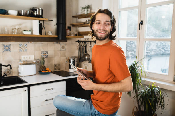 Portrait of a young man enjoying at home and surfing the net on tablet stock photo