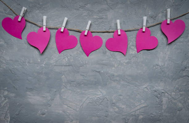 Pink hearts on rope with clothespins, on a grey background
