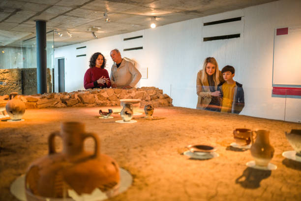 Three generations of one family at a National Museum of History, looking at a life-size replica of a Roman restaurant, low angle shot, many artifacts in foreground.