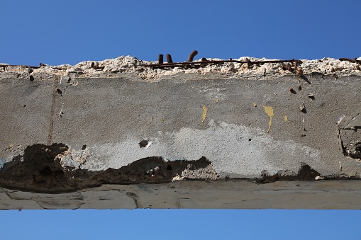 Reinforced concrete spalling damage in seaside humid weather and salty air conditions. Israel infrastructure problem: rusty rebar concrete damage.
