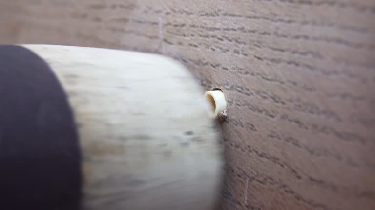 worker's hand inserts a plastic dowel pin into a drilled hole