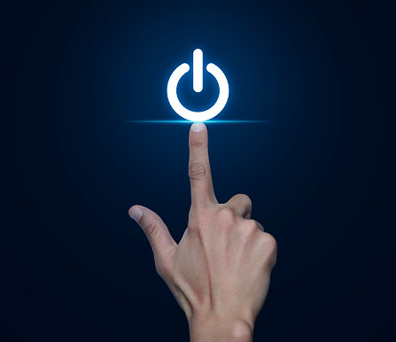 Hand pressing power button icon over blue background, Start up business concept