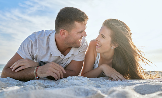 Love, ocean and couple laying on beach, man and woman relax on summer morning date. Travel, sea and happy couple on sand, spending time together in nature and romance on luxury vacation in Australia.