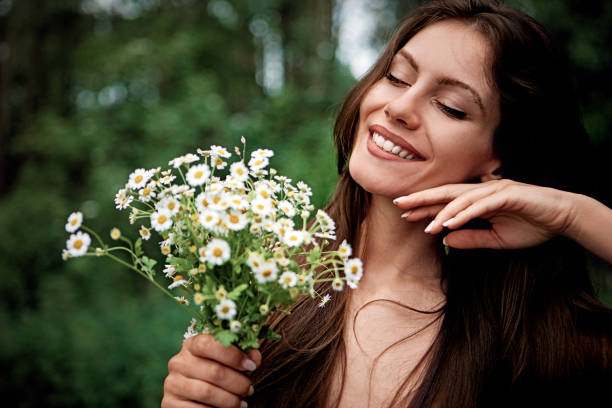 ritratto di giovane donna che tiene un bouquet di camomilla - german chamomile chamomile plant smelling flower foto e immagini stock