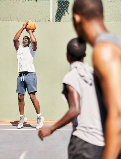Fitness, basketball and basketball player shooting in a training game, sports exercise or workout outdoors. Wellness, focus and healthy men enjoy playing on a basketball court as friends in Nigeria fitness, baloncesto y tiro de jugador de baloncesto en un juego de entrenamiento, ejercicio deportivo o entrenamiento al aire libre. bienestar, concentración y hombres sanos disfrutan jugando en una cancha de baloncesto como amigos en nigeria