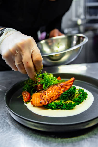istock chef hand preparing a gourmet salmon steak with broccoli on restaurant kitchen 1456210470