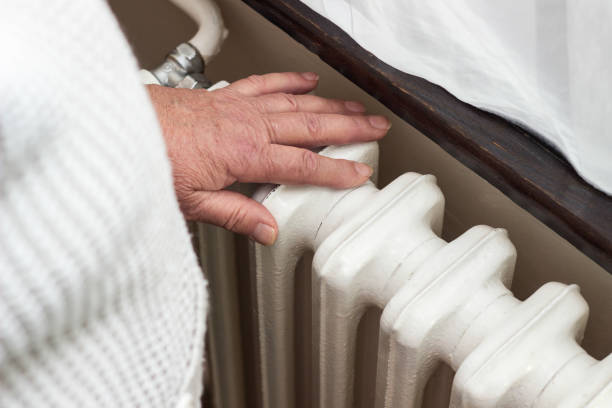 istock Senior woman warming hands on the heating radiator 1456210820
