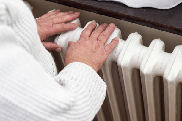 istock Senior woman warming hands on the heating radiator 1456210825