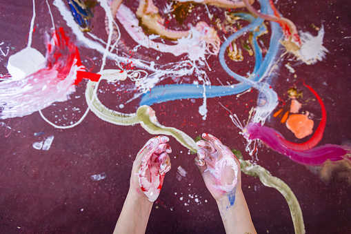 Messy hands of one Caucasian abstract artist, using his hands for painting with oil colors on canvas.