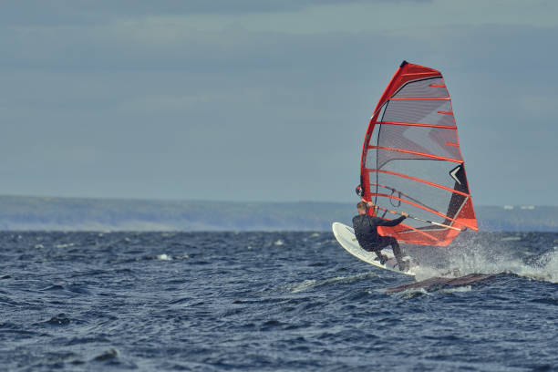 Man, a windsurfer, glides through the waves on a sailboard
