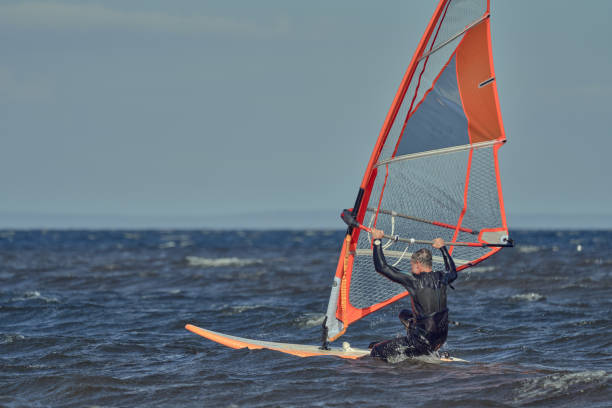 istock Man, a windsurfer, jumps on a sailboard 1456211873