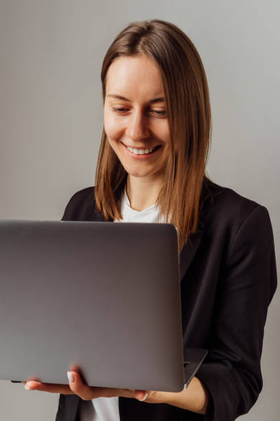 istock Smiling woman wearing black jacket is working at the laptop while smiling. 1456214967