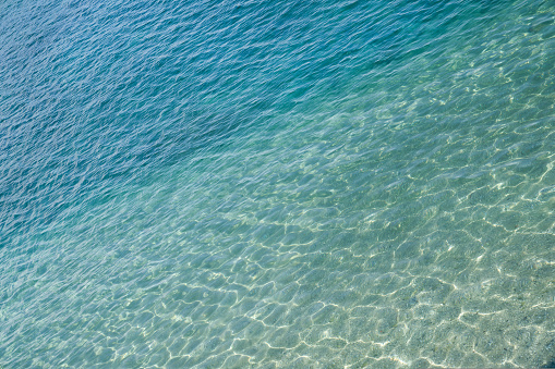 Marine water surface, sun's rays shimmer on water surface, diagonal lines, top view