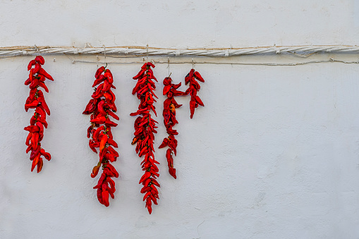 A string of red peppers drying in the sun.