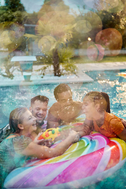 istock Young cheerful friends talking on inflatable raft at the pool. 1456216842