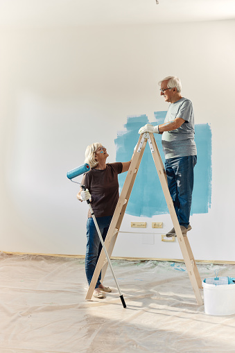 Workers from a painting company with a color swatch palette painting a wall isolated on white background