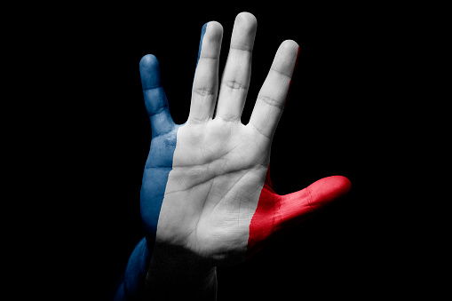 Rude man hand with flag of France in stop sign to anger, discrimination, racism, abuse on black background.