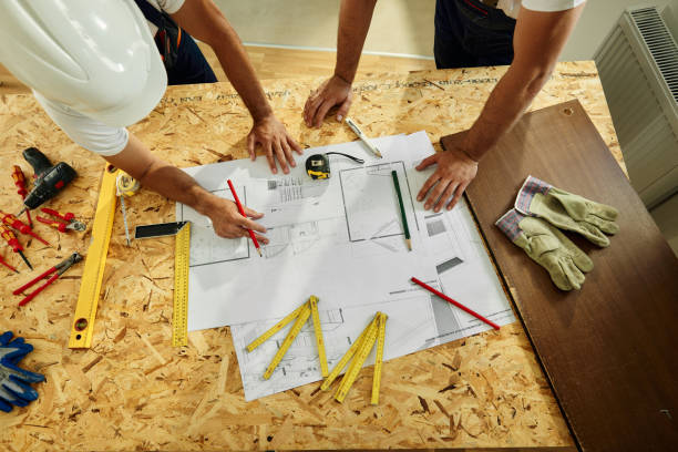istock Above view of manual workers examining blueprints on construction site. 1456218312