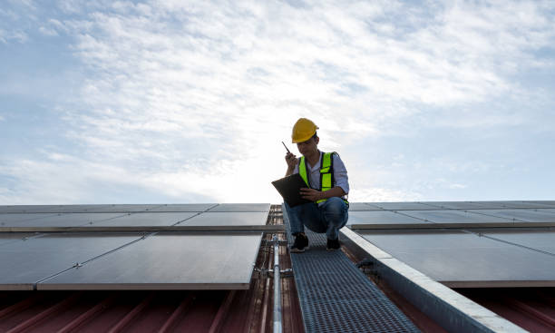 istock Engineer working setup Solar panel at the roof top. Engineer or worker work on solar panels or solar cells on the roof of business building 1456218411