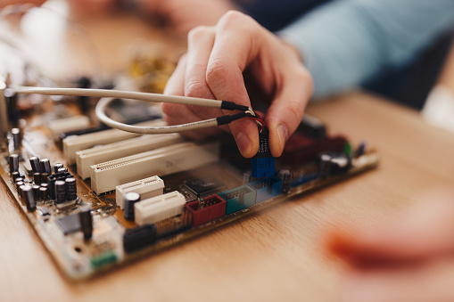 Close up of unrecognizable man repairing electrical components of a computer.