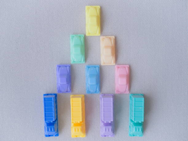 Concept image series of plastic toy cars and trucks in pastel colors illustrating situations. These photographs can be useful as dividers, illustrations, the introduction of an idea, a demonstration or a presentation. encuadre horizontal de una imagen conceptual que muestra una vista superior de una pirámide compuesta por coches en la parte superior y camiones en la base, sugiriendo una estrategia, un grupo solidario, complementariedad, relevo, refuerzo, una jerarquía